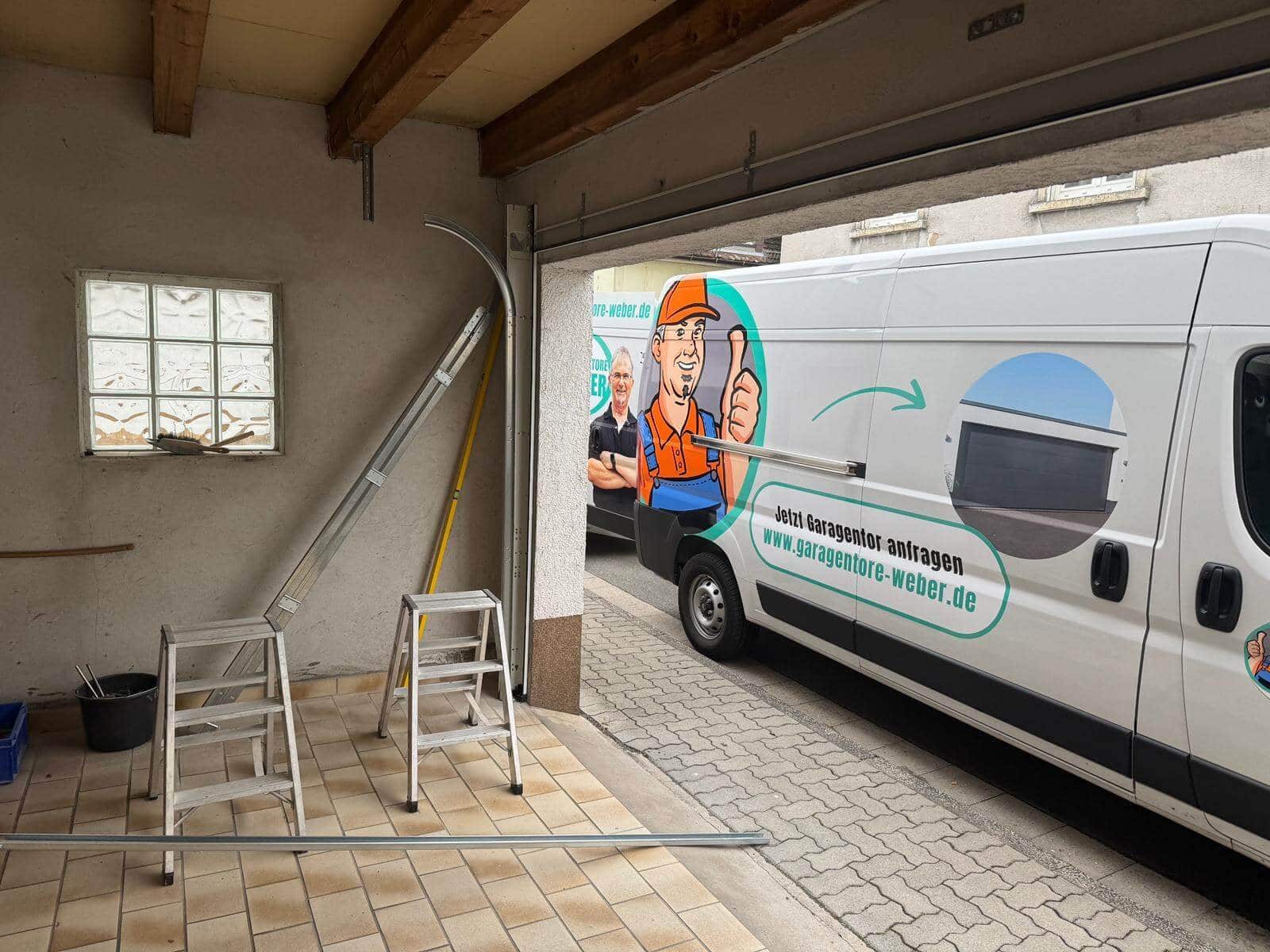 Zwei Monteure neben einem Servicewagen mit Garagentorteilen und Werkzeug